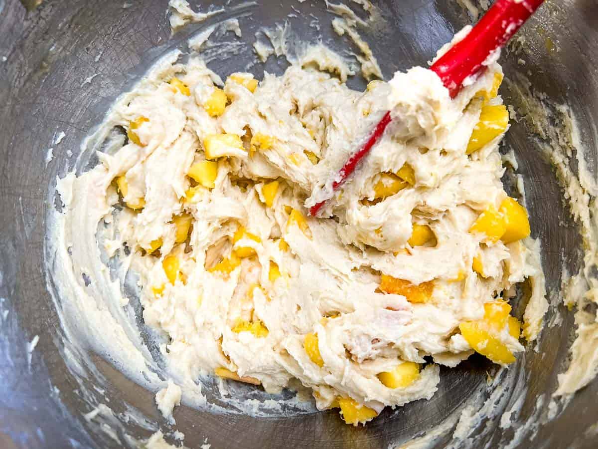 Gently folding the peaches into the cookie dough.