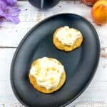 2 peaches and cream cookies on a black plate.