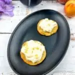 2 peaches and cream cookies on a black plate.
