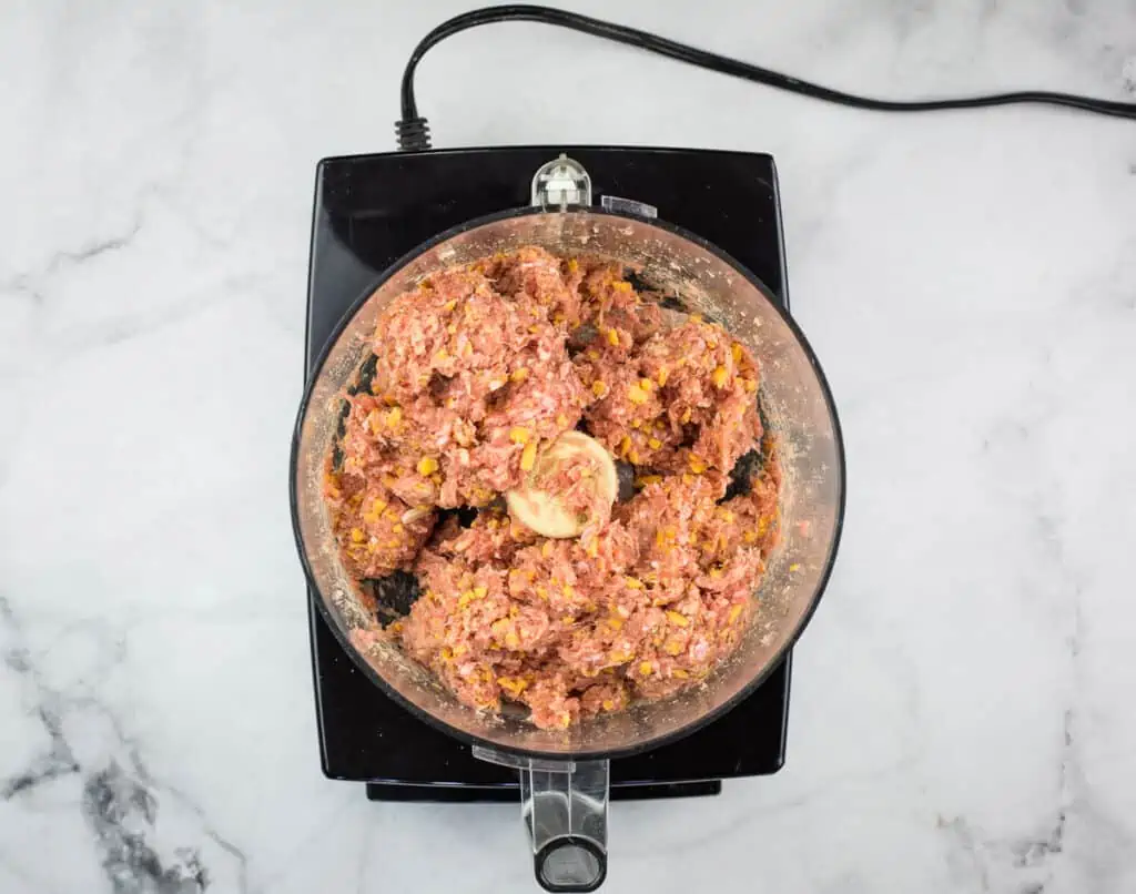 Pulsing the meat, cheese, and spices in a food processor.