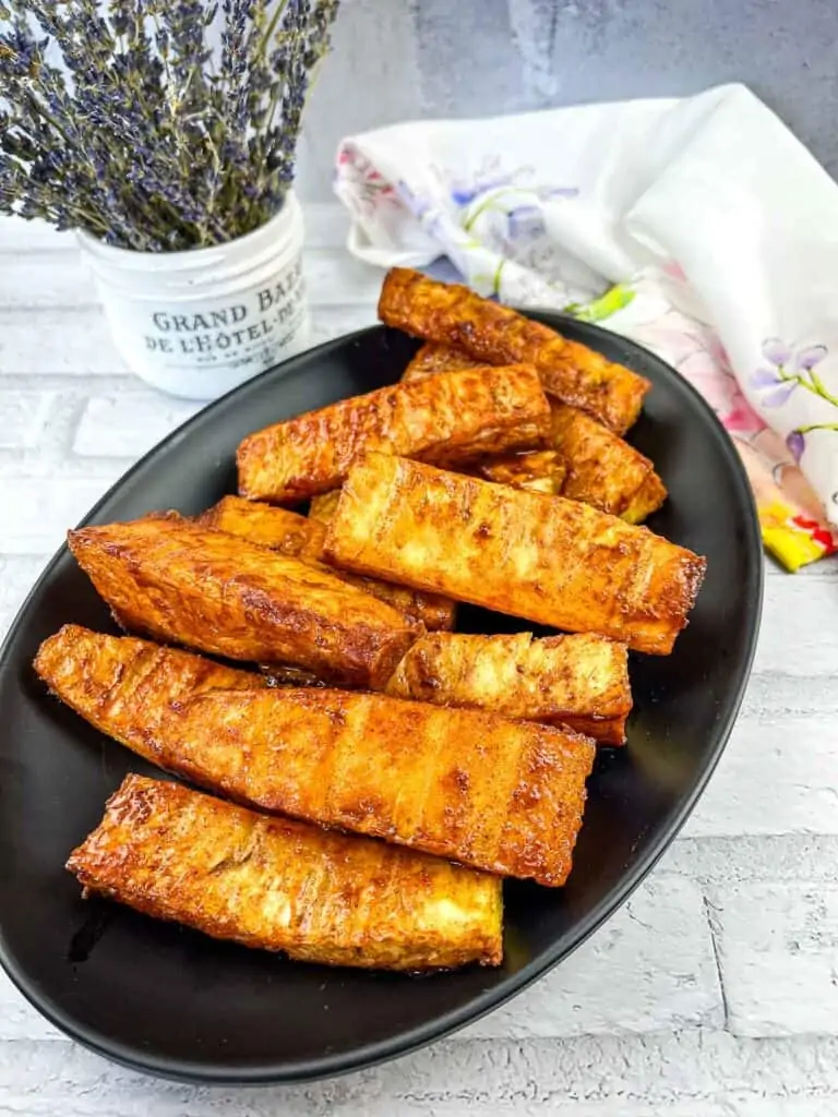 Sweet and spicy smoked pineapple spears on a black plate.