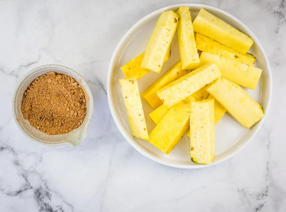 Pineapple cut into spears and a bowl of spice rub.