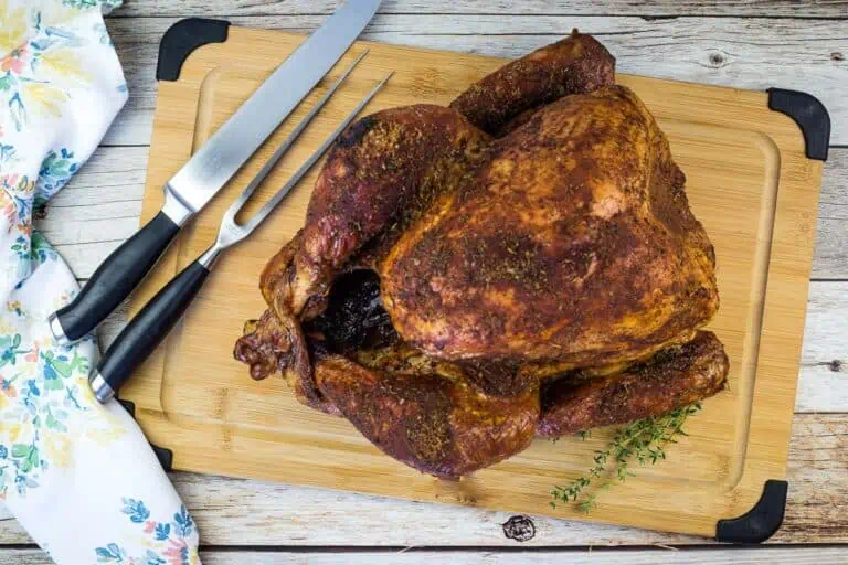 A smoked turkey on a wooden cutting board.