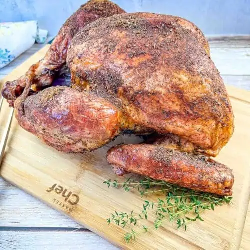 Whole Traeger smoked turkey on a cutting board.