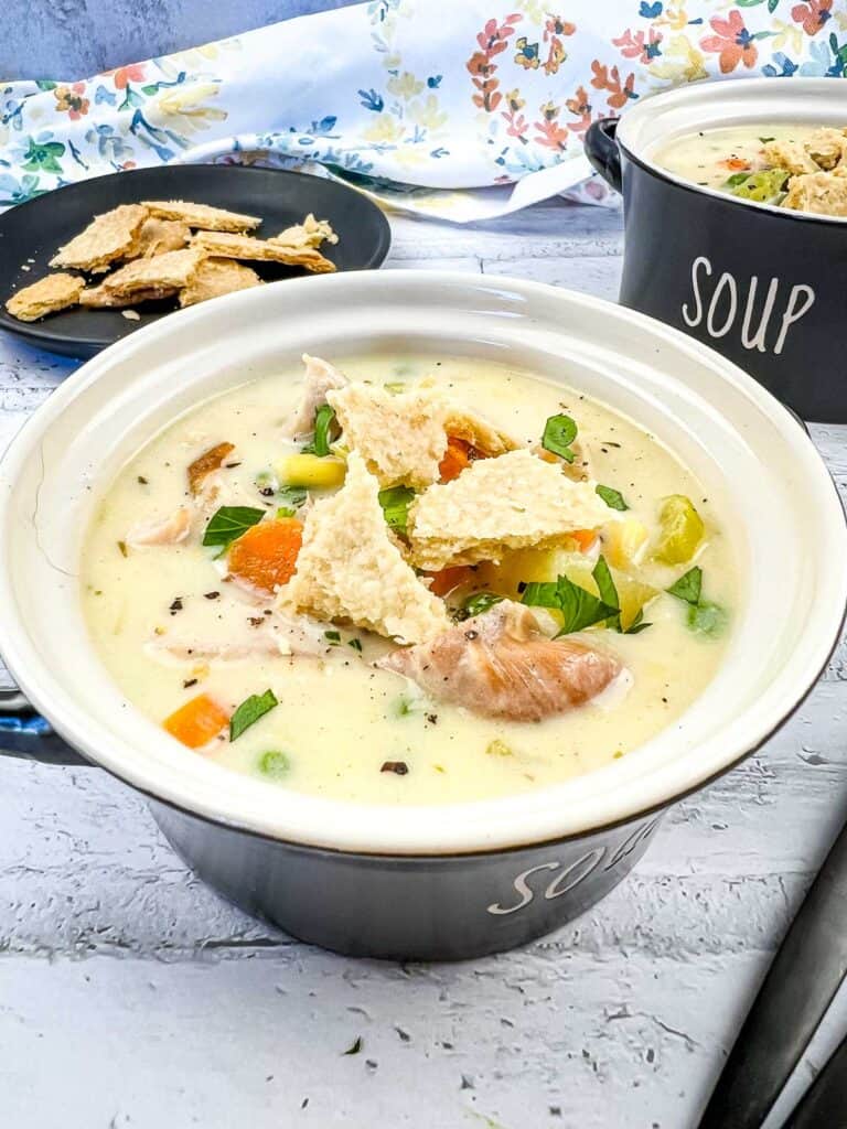 Turkey pot pie soup in a black soup bowl.