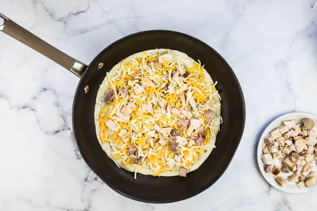 Diced turkey then another layer of cheese added to the tortilla.