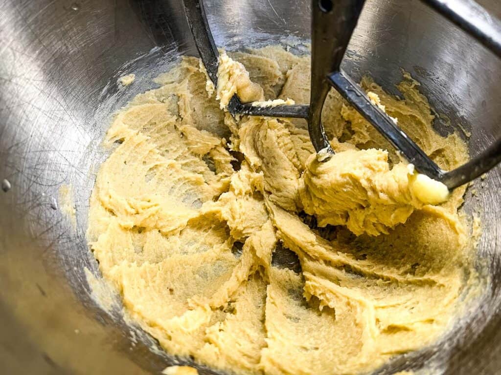 Creamed butter and sugar mixture in a mixing bowl with a paddle attachment, perfect for making sweet potato cookies.