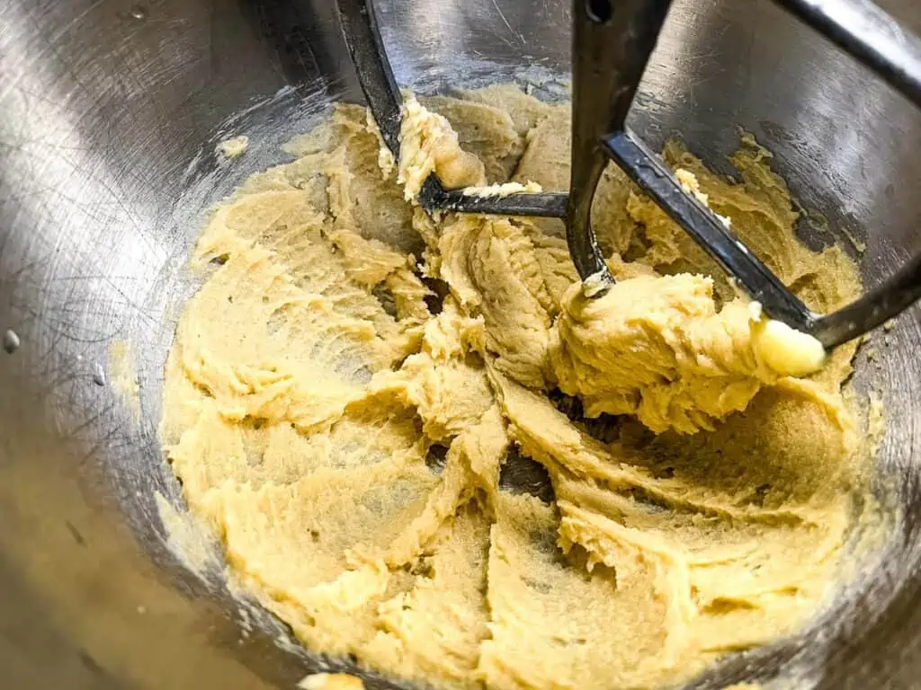 Creamed butter and sugar mixture in a mixing bowl with a paddle attachment, perfect for making sweet potato cookies.