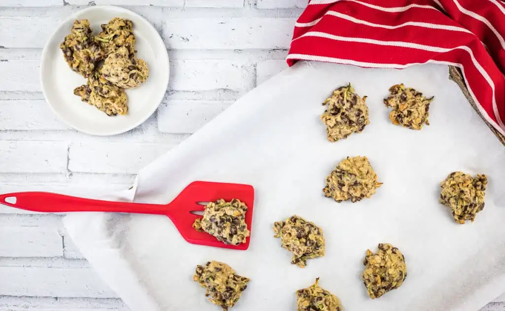 zucchini cookies with chocolate and pecans on a baking sheet.