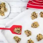 Zucchini Cookies with Chocolate & Pecans with Chocolate Chips and Oatmeal on a baking sheet with a red spatula.