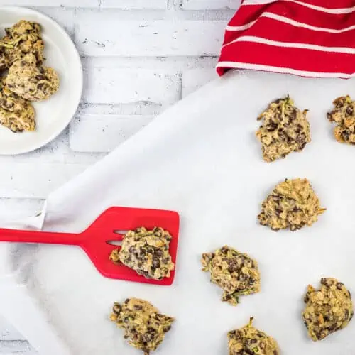 Zucchini Cookies with Chocolate & Pecans with Chocolate Chips and Oatmeal on a baking sheet with a red spatula.