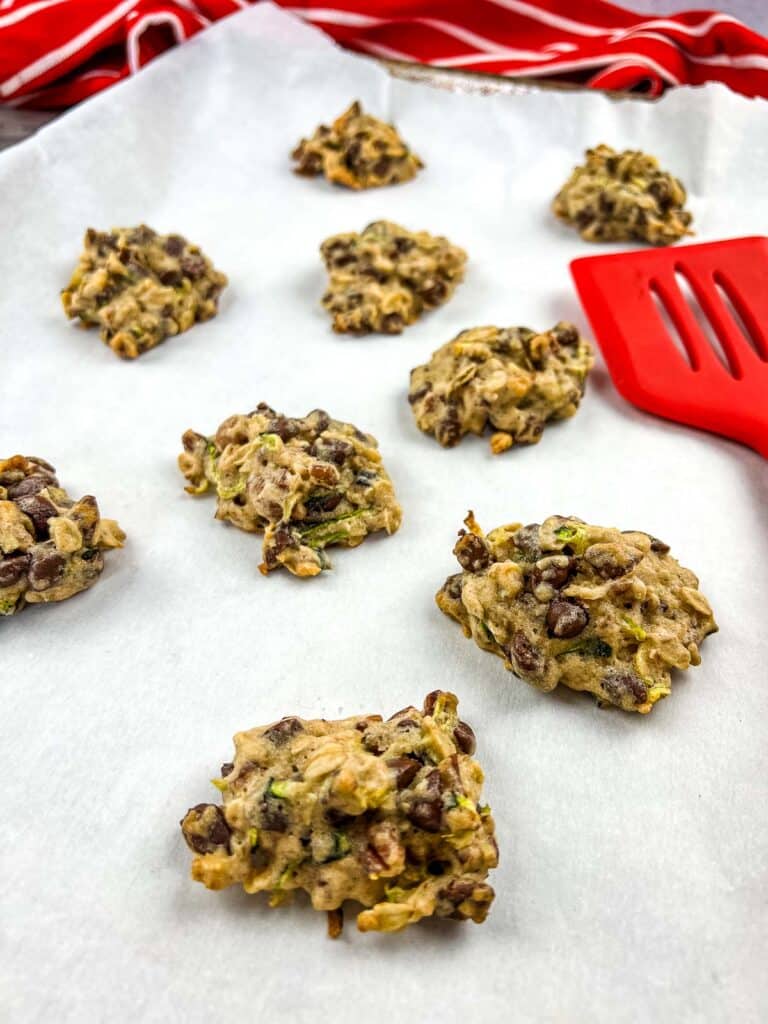 zucchini cookies with chocolate and pecans on a baking sheet.