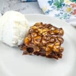Turtle Brownie on a plate with a scoop of vanilla ice cream.