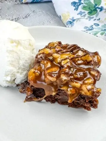 Turtle Brownie on a plate with a scoop of vanilla ice cream.