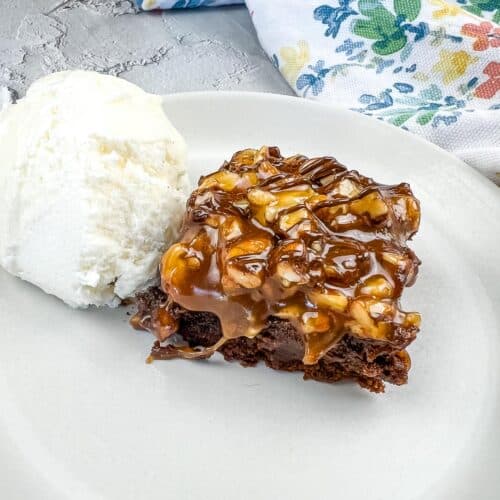 Turtle Brownie on a plate with a scoop of vanilla ice cream.