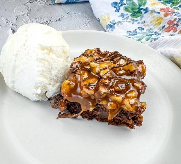 Turtle Brownie on a plate with a scoop of vanilla ice cream.