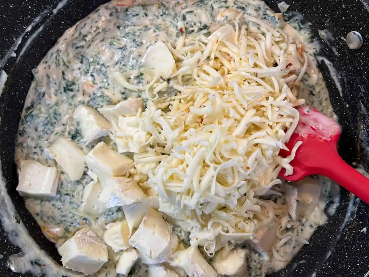 Mixing in the brie and cheeses into the spinach and cream sauce.