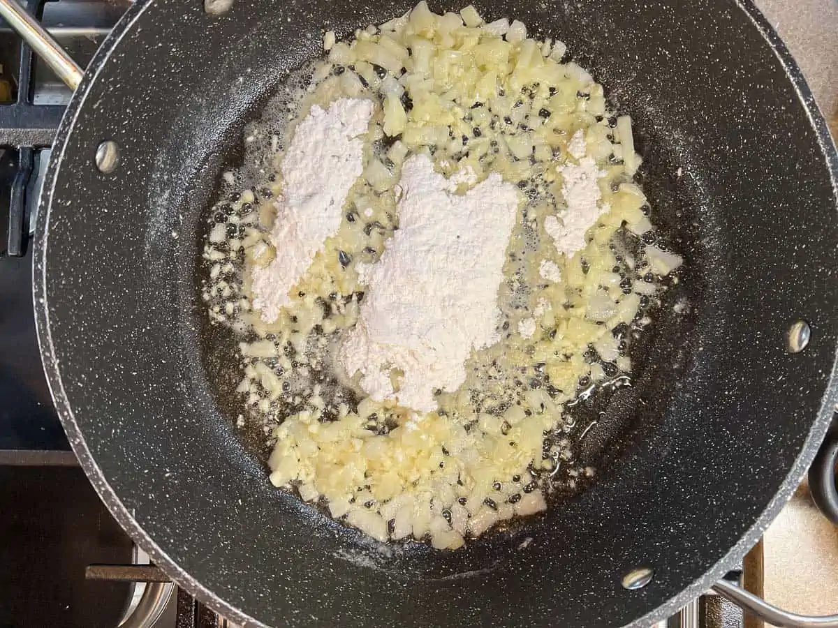 Mixing the flour into the cooked onions and garlic.