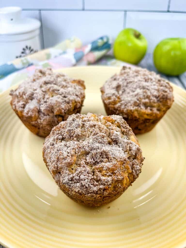 Apple, Date and Walnut muffins on a plate with green apples in the background.