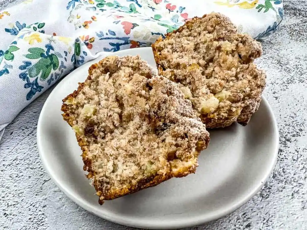 A sliced Apple, Date, and Walnut Muffin on a plate.