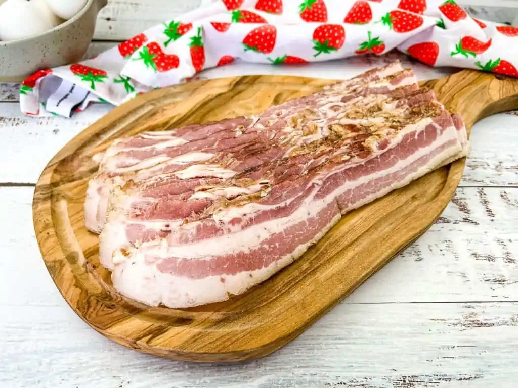 Homemade sliced bacon on a cutting board.