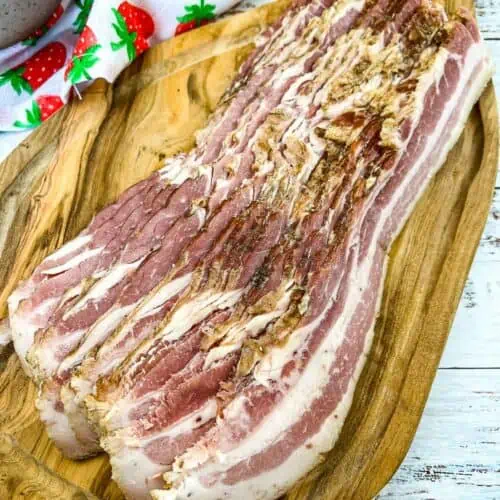 Homemade bacon sliced on a cutting board.