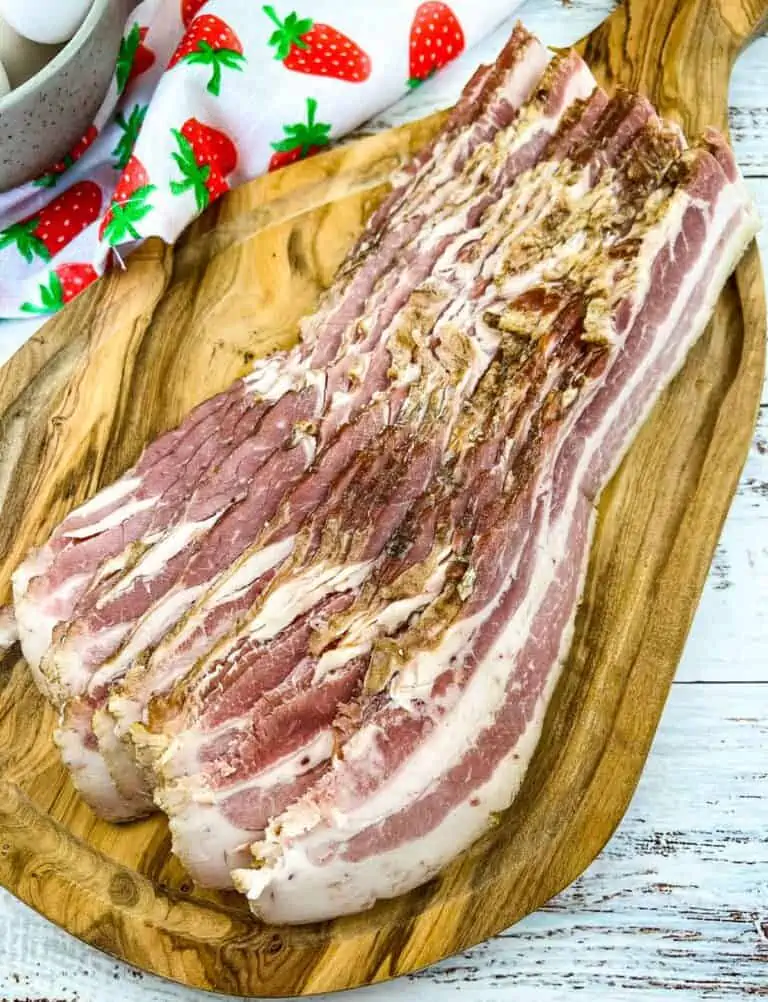 Homemade bacon sliced on a cutting board.