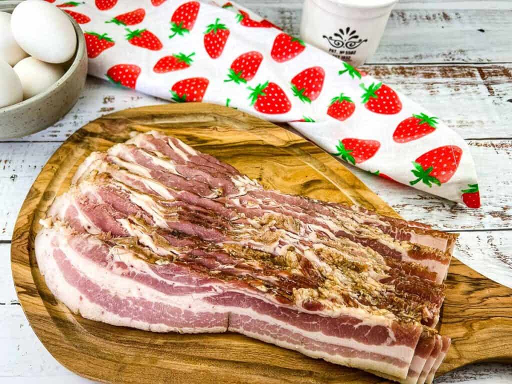 Sliced homemade bacon on a cutting board.