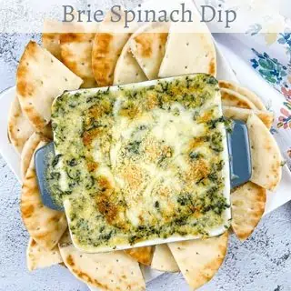 Brie Spinach Dip in a bowl with pita wedges around it.