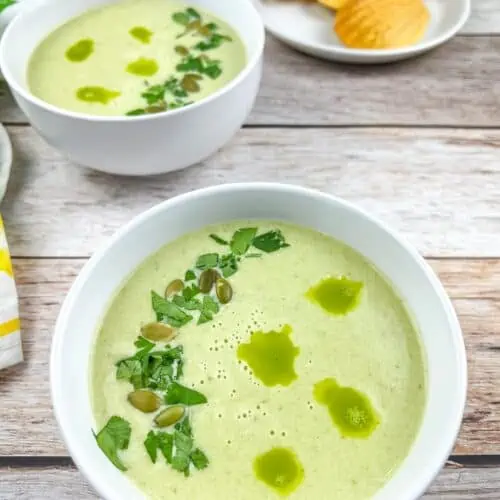 Two bowls of Cream of Jalapeno Soup with cornbread madeleines in the background.