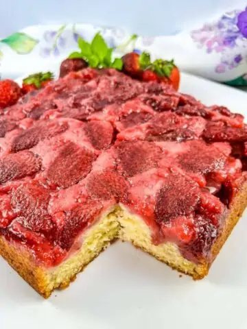 Strawberry Upside Down Cake on a plate with a slice cut out of it.