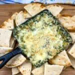 Spinach and Brie Dip in a cast-iron dish with pita chips around it.