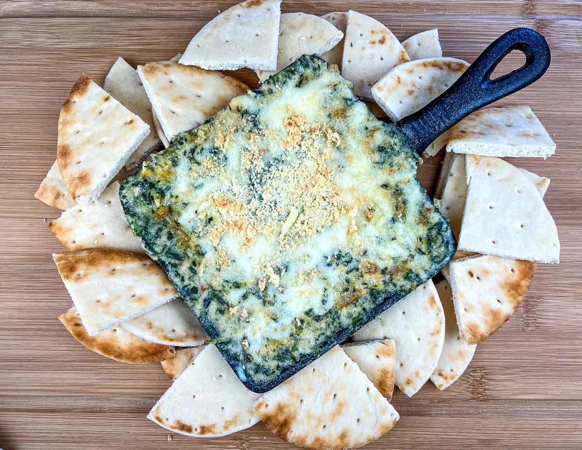 A top-down shot of Spinach and Brie Dip with pita wedges around it.
