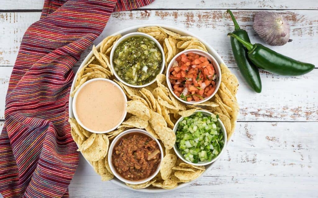A selection of salsas on a platter with tortilla chips.