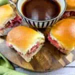 Smoked French Dip Sliders on a cutting board with jus in the middle.