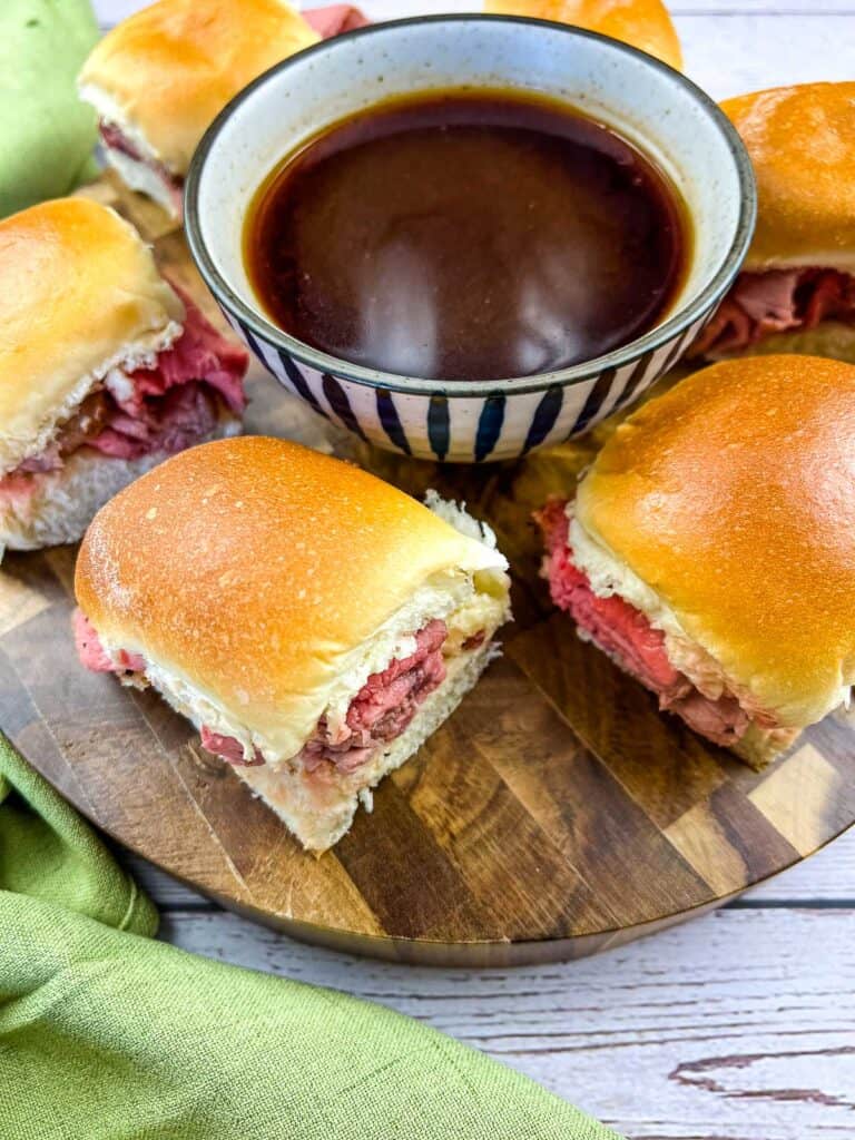 Smoked French Dip Sliders on a cutting board with jus in the middle.