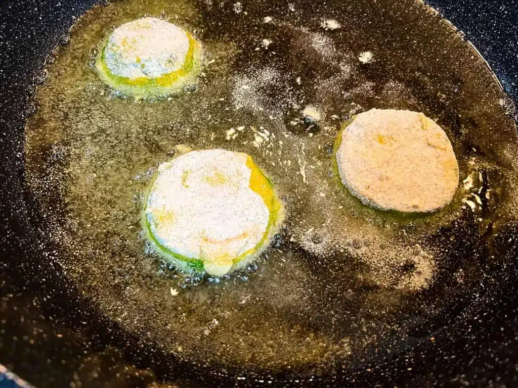 Shallow frying the battered tomatillos in oil.