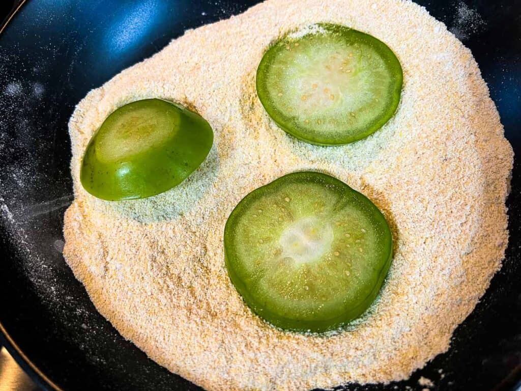 Tomatillo slices coated in the flour mixture.
