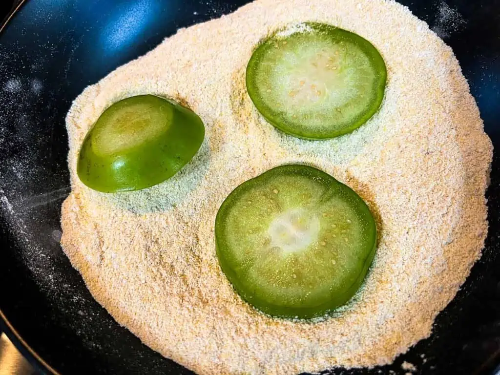 Tomatillo slices coated in the flour mixture.