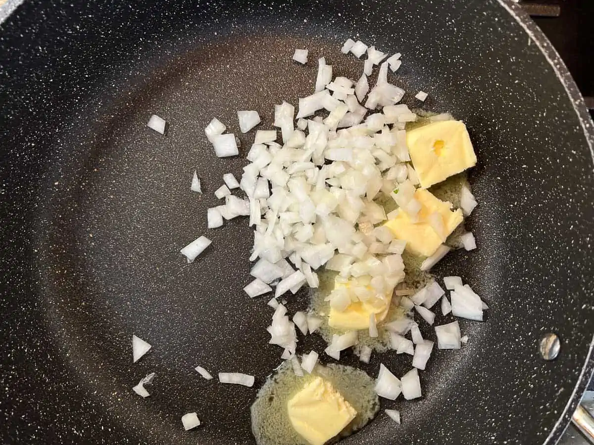 Sauteing the onions in the butter in a skillet.