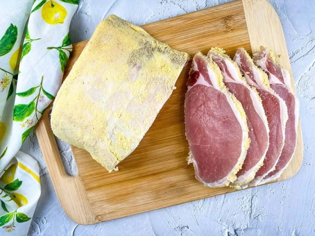 A top-down shot of raw sliced peameal bacon on a cutting board.