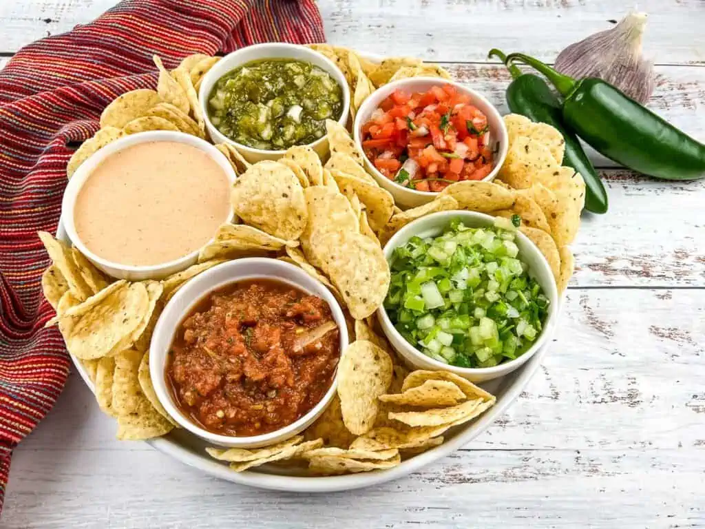 Dips, salsas, and pico de gallo in a serving bowl with tortilla chips.