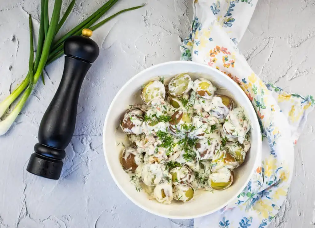 A top-down shot of Potatoes with Sour Cream and Bacon in a white bowl.