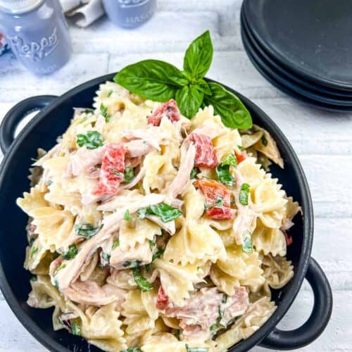 Rotisserie Chicken Pasta Salad in a black bowl with serving plates in the background.