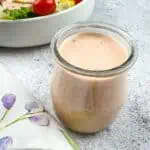 Russian Dressing in a glass jar with a salad in the background.