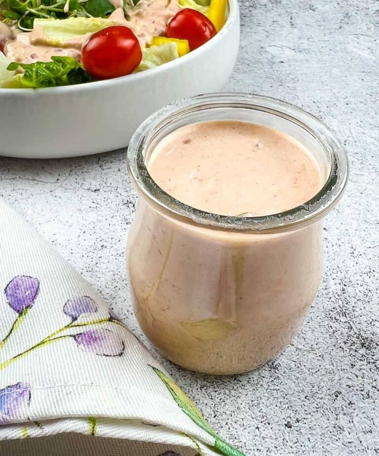 Russian Dressing in a glass jar with a salad in the background.