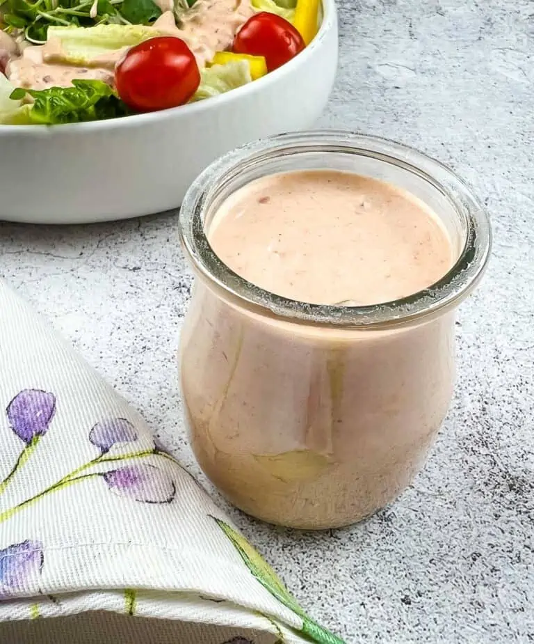 Russian Dressing in a glass jar with a salad in the background.