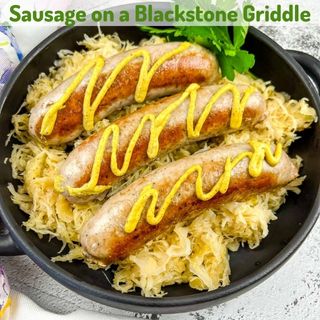Sausage on a bed of sauerkraut in a black pan.