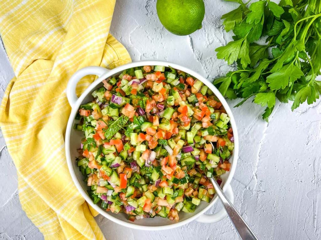 A top-down shot of Shirazi Salad in a white bowl.