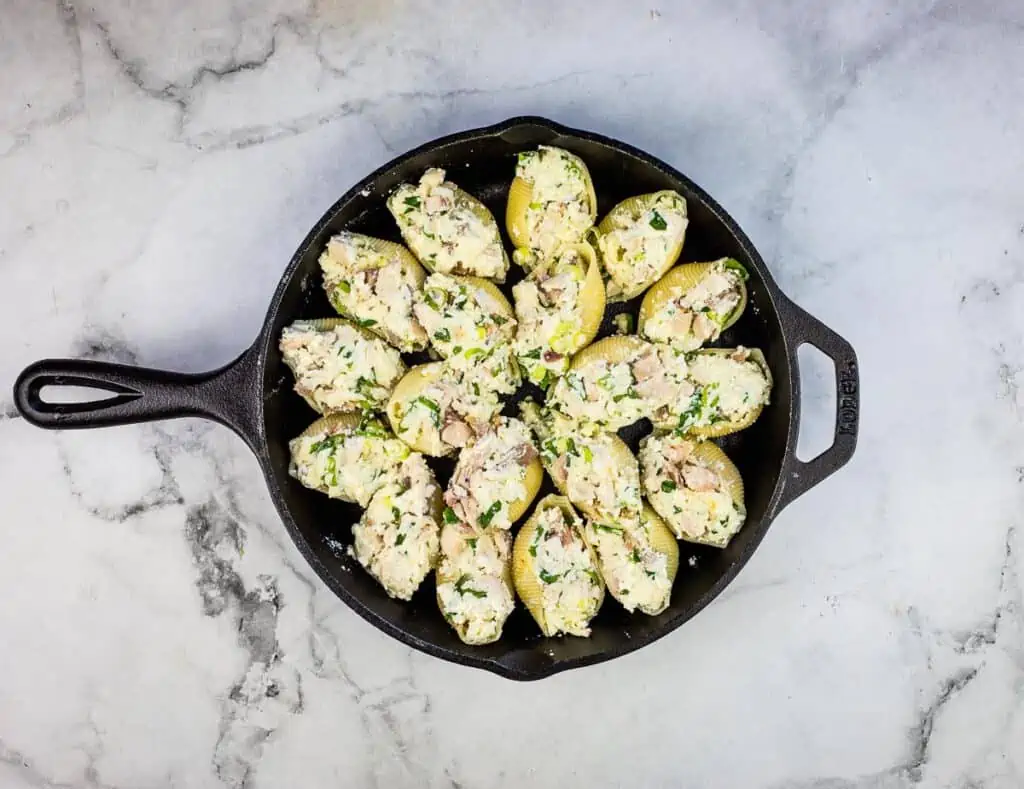 Stuffed pasta shells arranged in a cast iron pan.